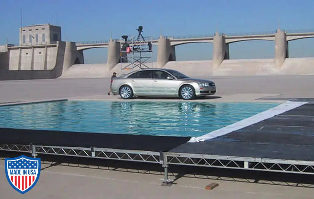 Car on film set with steel deck rigging and water effect in outdoor location for grip and filming.