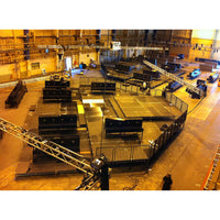 Steel deck platform setup in a large indoor film studio with rigging equipment and grip tools.